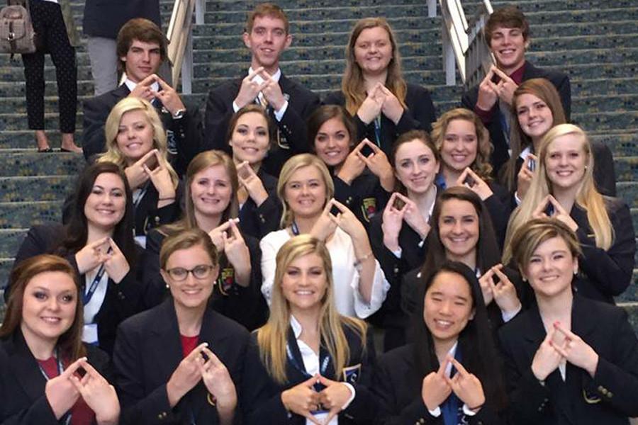 Students pose, holding up the DECA symbol as they represent Kansas at the International Career Development Conference. 