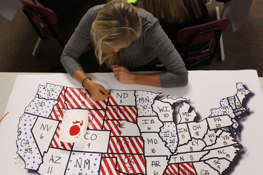 Senior Katie Brungardt puts the finishing touches on a poster predicting the electoral college votes for the 2016 Presidental Election. 