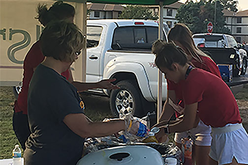 Astra Bank employees serve food at tailgate.   