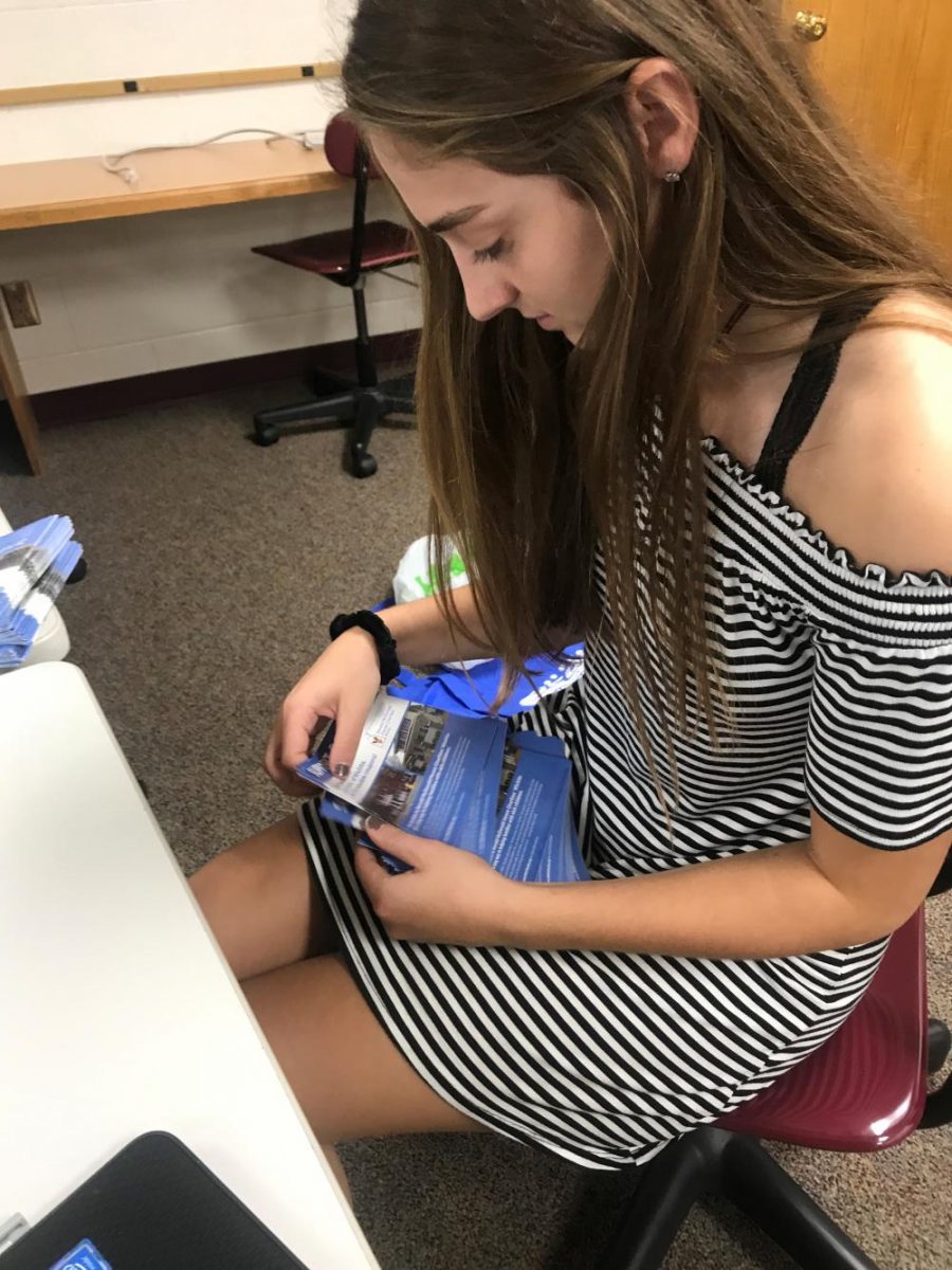 Junior Kallie Leiker counts out 30 coupon books for each of the DECA members. Each student is asked to sell their share, and those turned back in will go to the local McDonalds for them to sell.