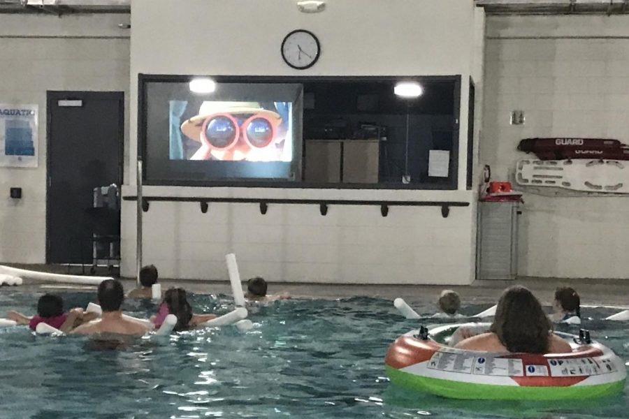 The public attends the movie while enjoying the comfort of a pool.