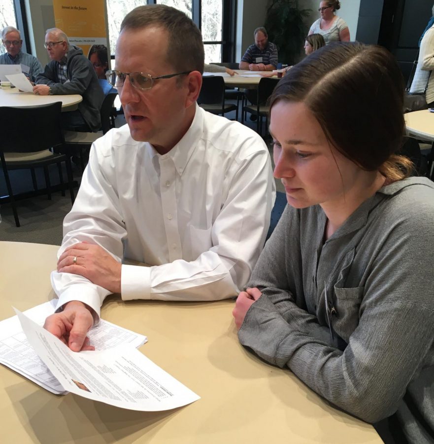 Senior Lisa Schoenberger and Principal Martin Straub look over the handout for the Neighborhood Project. The project was put together by a committee with the intent to bring together members of our community.