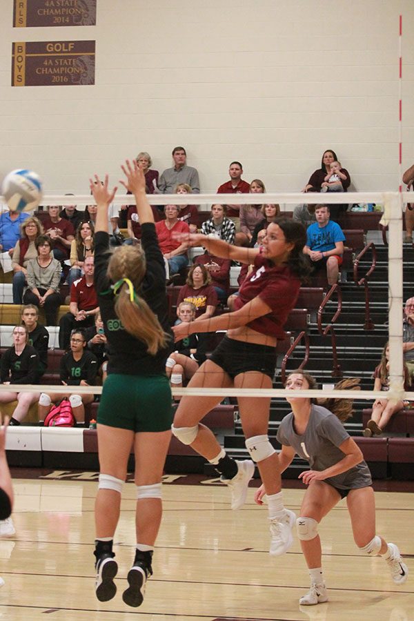 At the recent home game against Salina South, Tasiah Nunnery is making a kill between two blockers. 