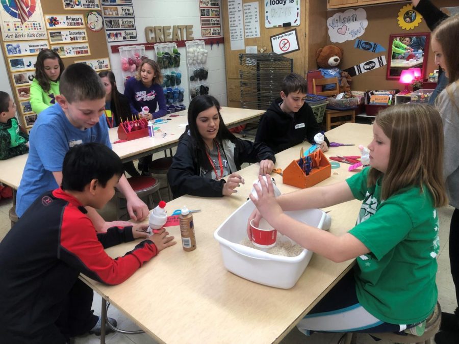 Junior Peyton Niernberger helps fourth grade students make snowmen crafts. 