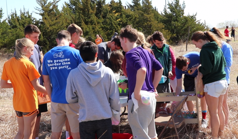 Student circle around the prize table in the outdoor classroom. Students took the slips of paper found in each of the eggs to the table to claim their prizes. 