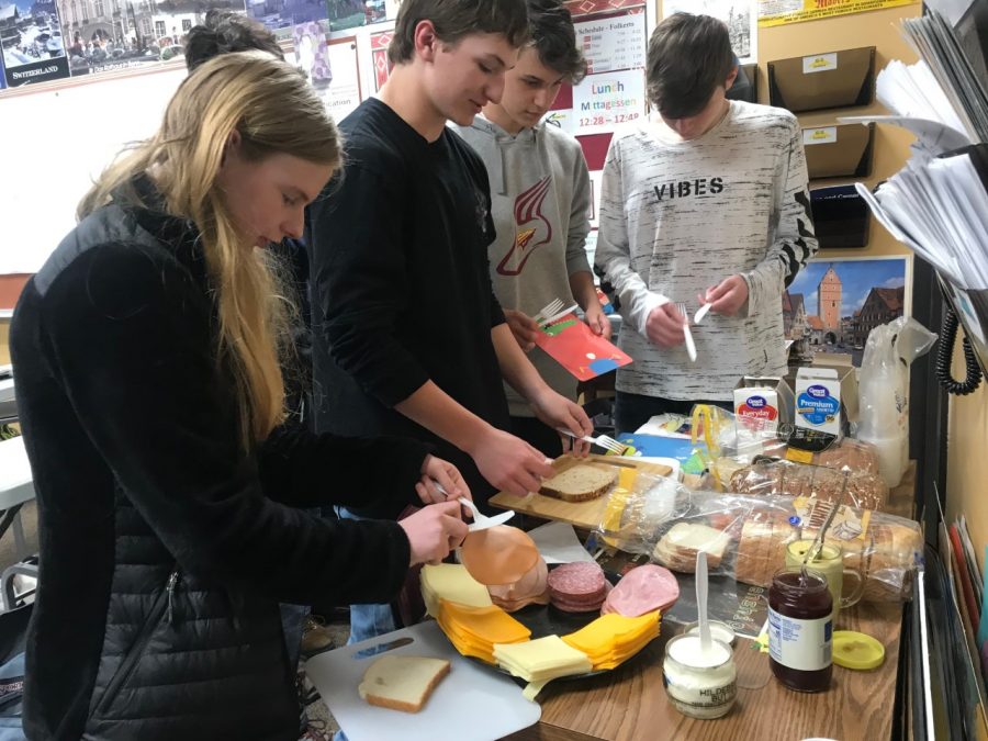 Students gather around the table to try a German continental breakfast on April 12.  The breakfast consisted of bread, sliced meat, cheese, butter, mustard and jam.