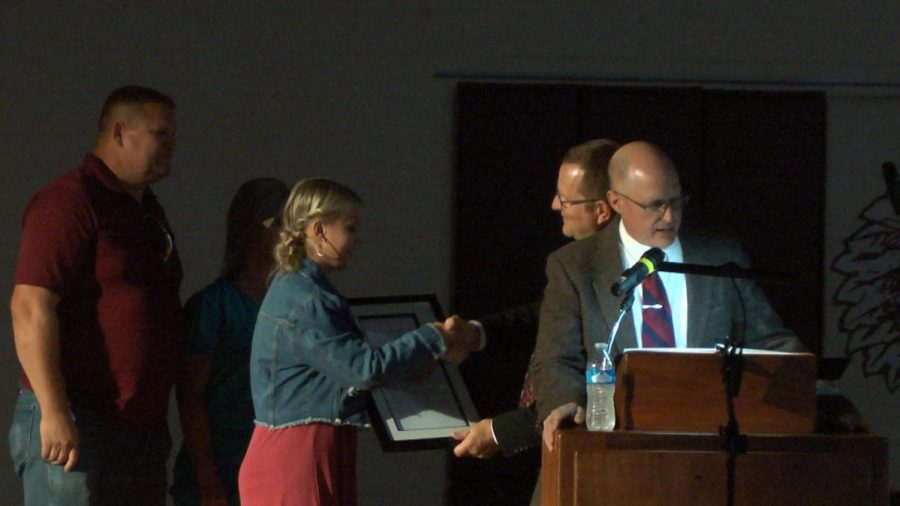 Senior Taylor Weidenhaft shakes principal Martin Straubs hand during the homecoming formal assembly. Weidenhaft was recognized for being a Nation Merit Commended student for her work on the 2019 PSAT/NMSQT.