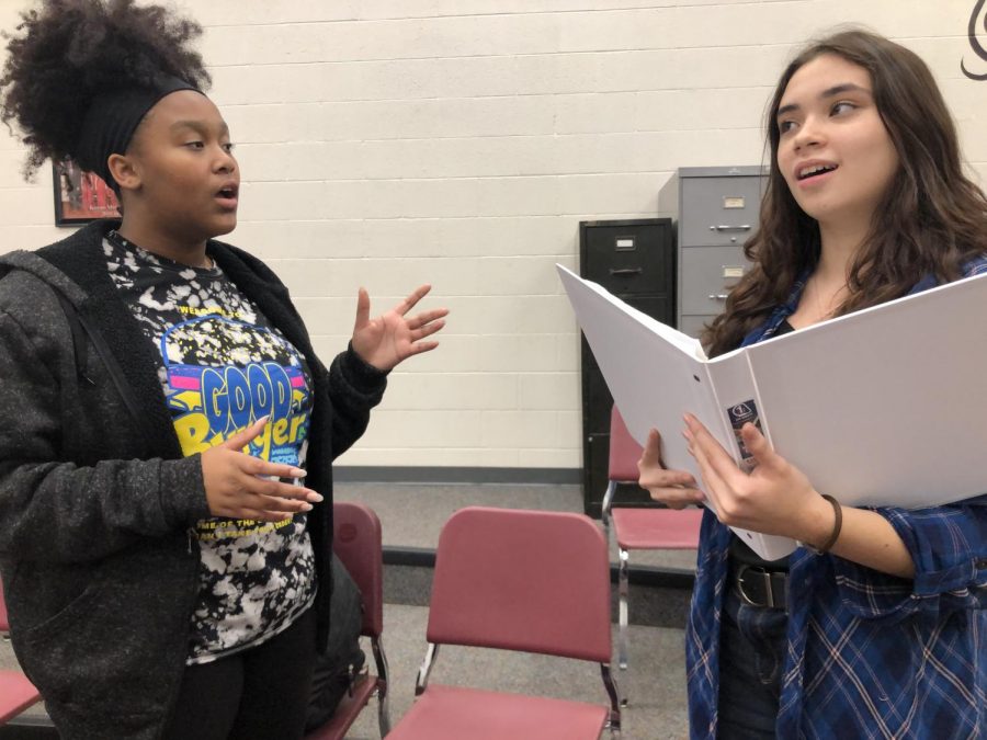 Junior Alisara Arial helps sophomore Shirley Lee run through the lyrics to her song before the showcase at the Hays Optimist Club meeting at Whiskey Creek. The performances for this years musical, Anything Goes, will be Nov. 14-17.