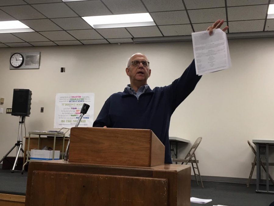 Director Bill Gasper holds up the informational packet that was passed out during the meeting. The packet contains information about auditions as well as the participation agreement that must be turned in to the office by Dec. 4.