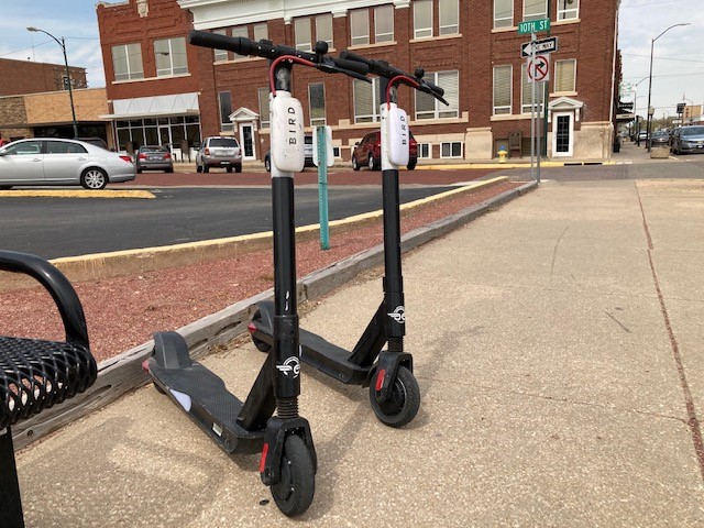 The electric scooters are usually parked on a sidewalk near a bike rack. They should be parked facing the street and out of the way of pedestrians and traffic.