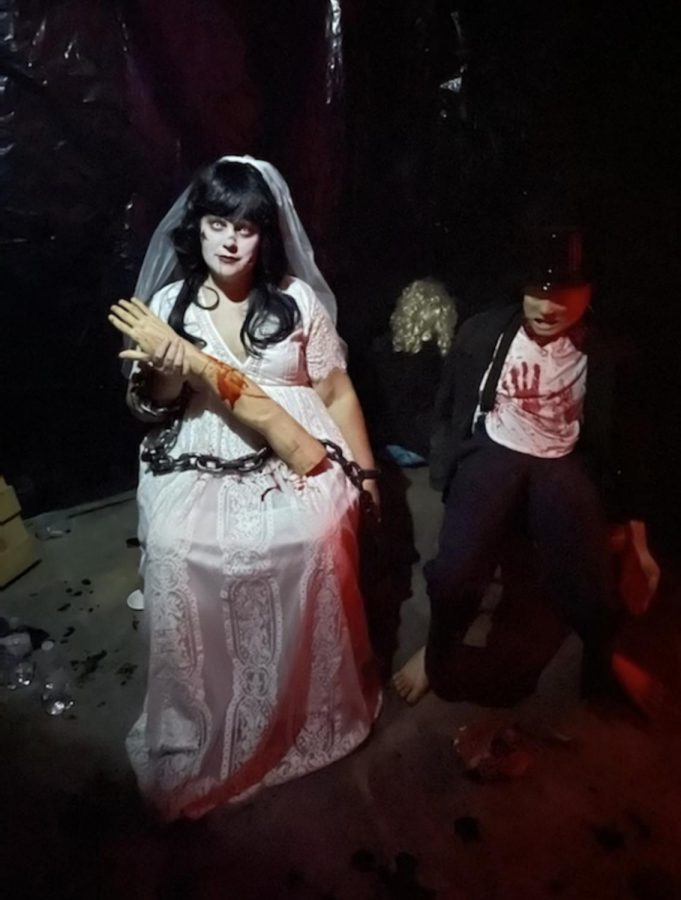 An actor in the haunted house sits in wait for customers to turn the corner into her room.