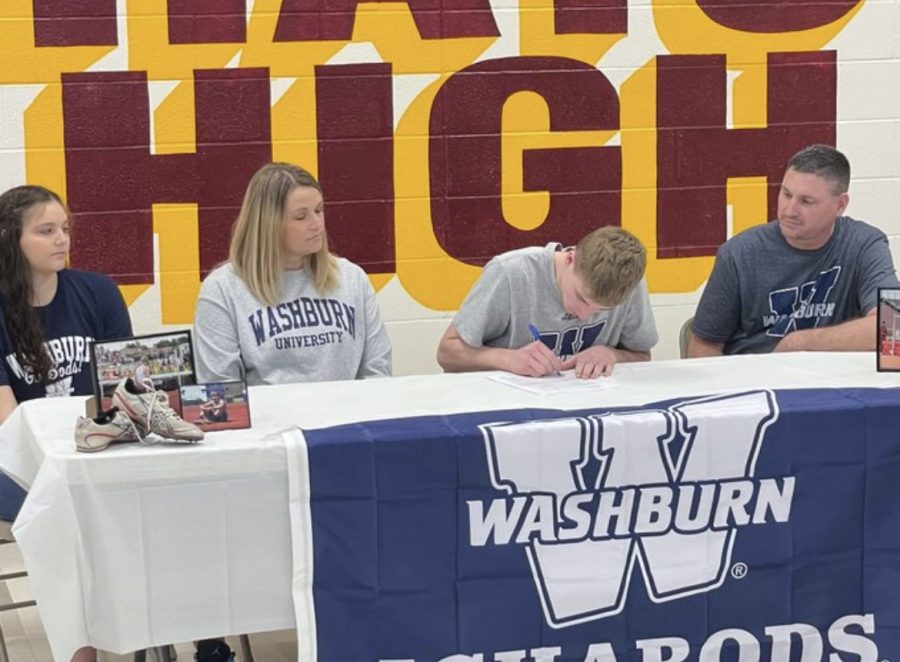 Senior+Jordan+Dale+accompanied+by+his+family%2C+signs+in+the+HHS+cafeteria+to+Washburn+University+for+Track+and+Field.