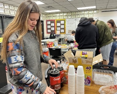 Freshman Mia Schlegel gets a cup for her drink on Dec. 9 in her PRIDE Time teacher Jessica Augustines classroom. Each student brought a food or drink to share with the class, such as chips and dips, cookies and smores brownies. The PRIDE Time party put me in the Christmas spirit, Schlegel said.