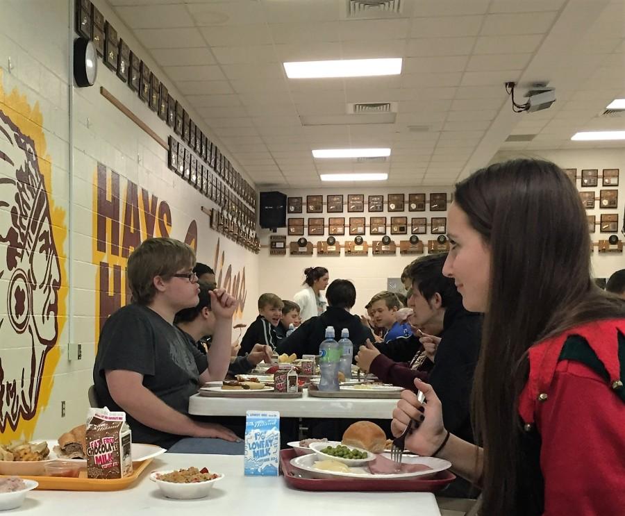 The table underneath the clock in the lunchroom is reserved for teachers. However, it is filled with students, leaving no room for the teachers to sit. 