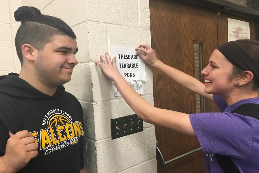 Senior Cooper Flores watches while sophomore Hannah McGuire posts her tearable puns on the wall. 