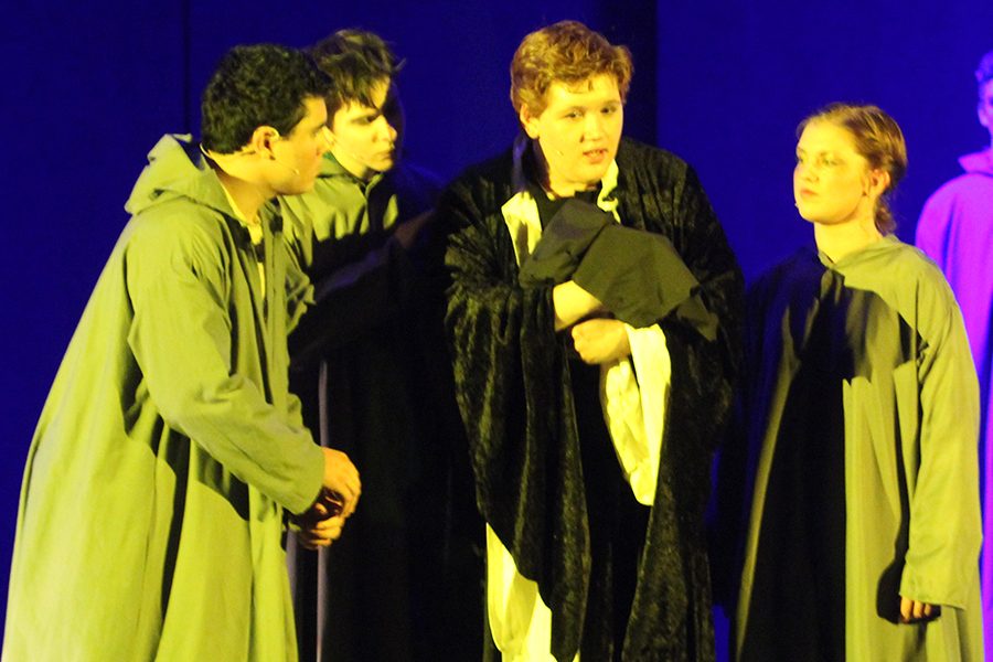 Father Claude Frollo (senior Eric Adams) holds a baby whom he names Quasimodo, or half-formed. Monks Victor, Hugo, and Laverne (seniors Michael Hernandez, Dawson Rooney, and Sarah Wyse) stand next to him, regarding him, as he decides what to do with the baby (Bells of Notre Dame).
