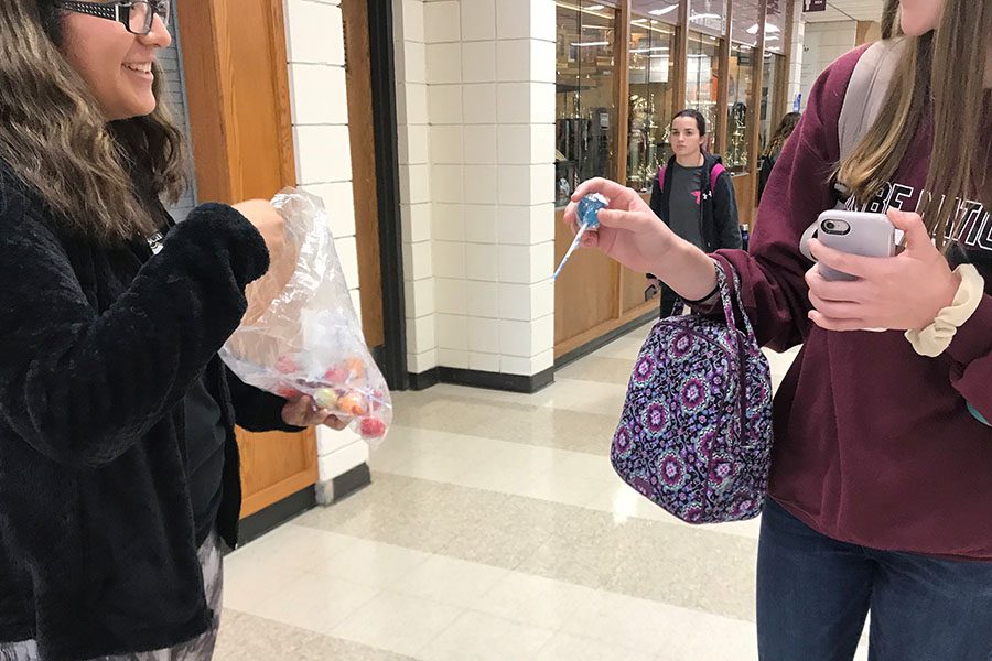 Junior Joanna Carillo sells a lollipop to raise funds for her trip to Ireland and Scotland. The trip will cost about $5,000.