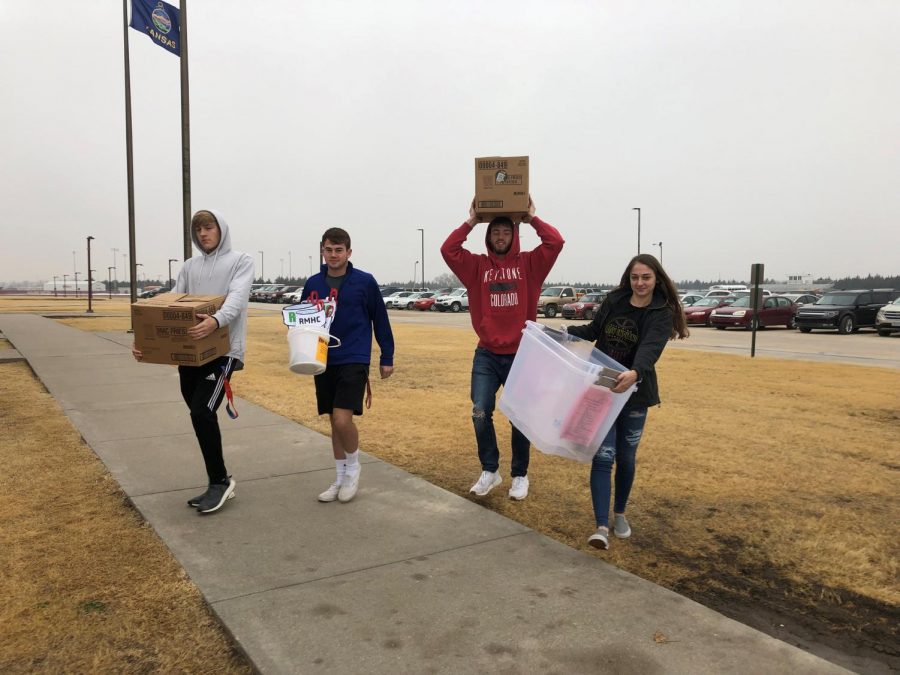 Senior DECA members Connor Teget, Peyton Thorell, and Kallie Leiker carry things for the community service project inside. Leiker carries buckets that will be used for the collection at Dillons on Dec. 8.
