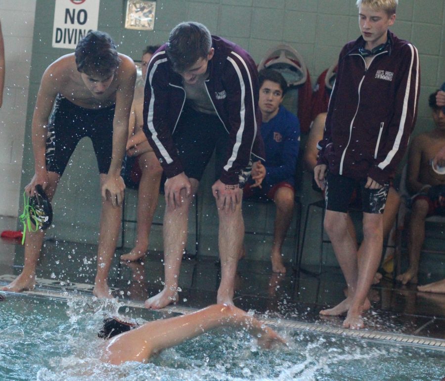 Swim team cheers on junior Carson Ackerman as he finishes the last leg of his race.