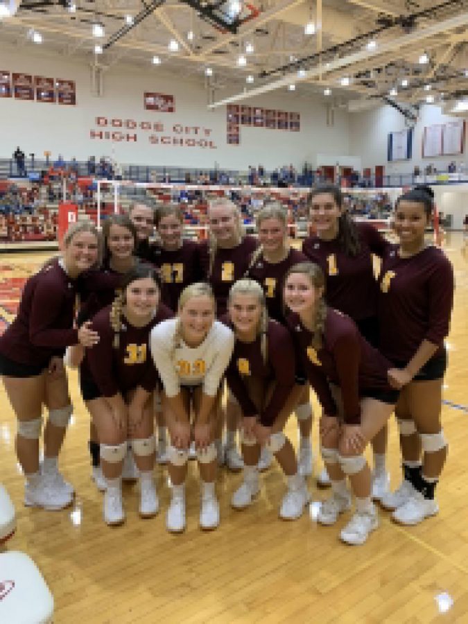 The varsity volleyball team smiling for a picture in between games at Dodge City. 