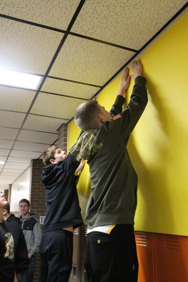 The sophomores hang up a yellow poster in their hallway for the decorating competition.