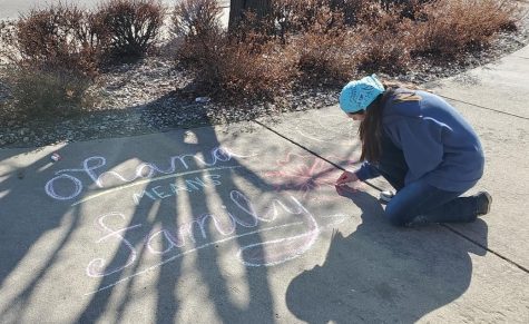 Junior Caitlin Leiker completes a chalk drawing on someones driveway. Leiker drove around leaving positive chalk messages for different friends and acquaintances as well as leaving drawings in front of the Hays Medical Center. Its been a pretty difficult during this time, especially for people who live alone, Leiker said. I figured the least I could was try to spread some positivity.