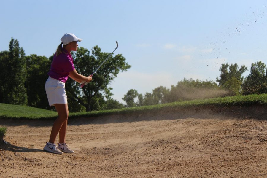 Varsity member Abbie Norris shoots out of the sand and on to the green at Smoky Hill Country Club.