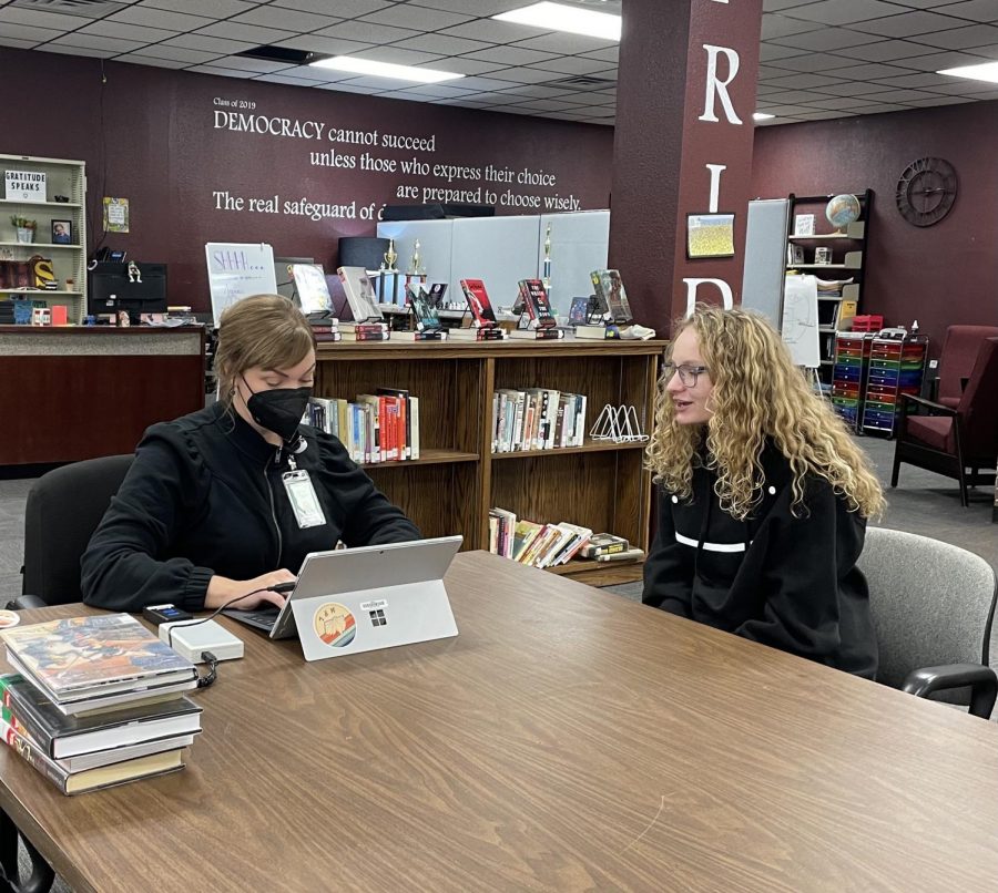 Junior Kaley Rajewski has her library card looked up and updates information with Holly Ray from the Hays Public Library. 