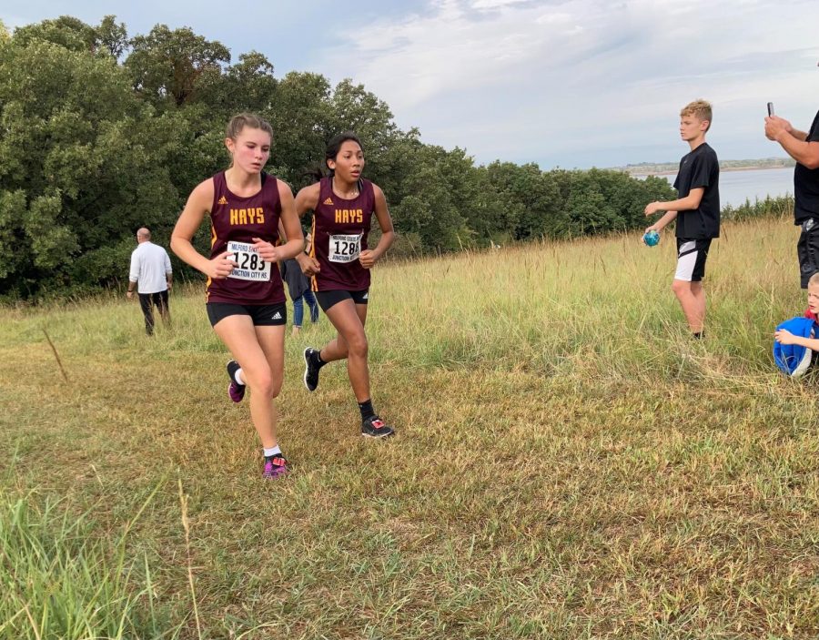 Sophomore Brynn Kinderknecht (left) and junior Nayeli Cisneros (right) run next to each other as they near the finish line.