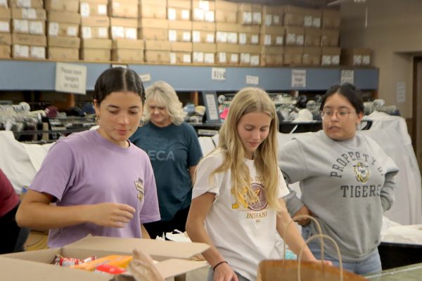 Juniors Aralen Maupin, Ava Biggs, and Mitzil Carrillo Maldonado stand in a line waiting for the next item to be passed down to be packaged. 