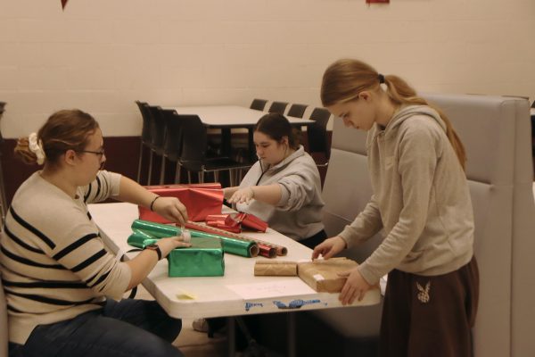 NHS members help wrap gifts for the families. 