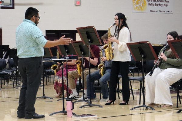High school band director Hector Hernandez directs, as senior Keira Vilaysing performs a solo on her saxophone at the All-City Band Concert on May 13.