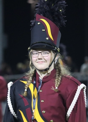 At a Hays High football game, senior Elizabeth Gerstner smiles for the camera as she prepares to use her instrument.